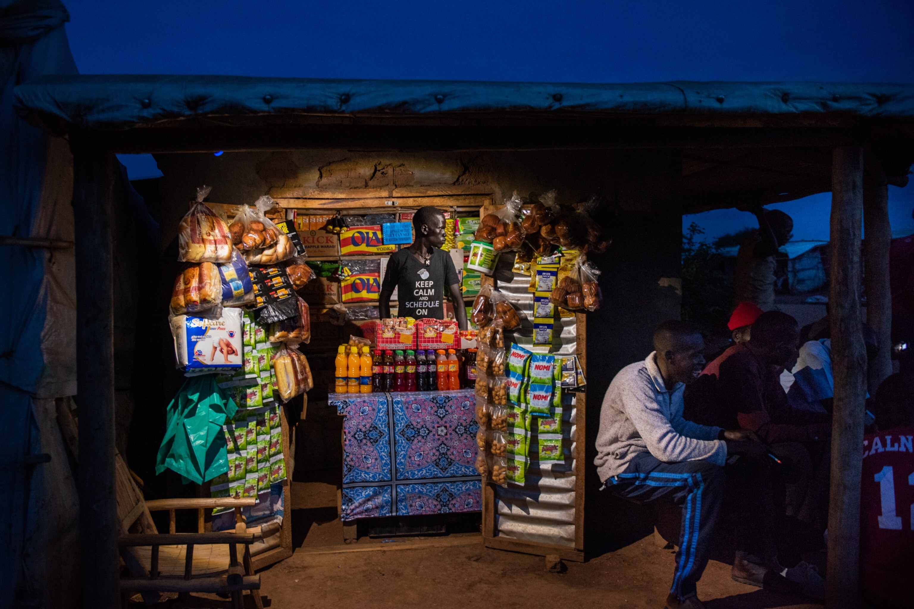 A trader at a lit kiosk in the evening in West Nile