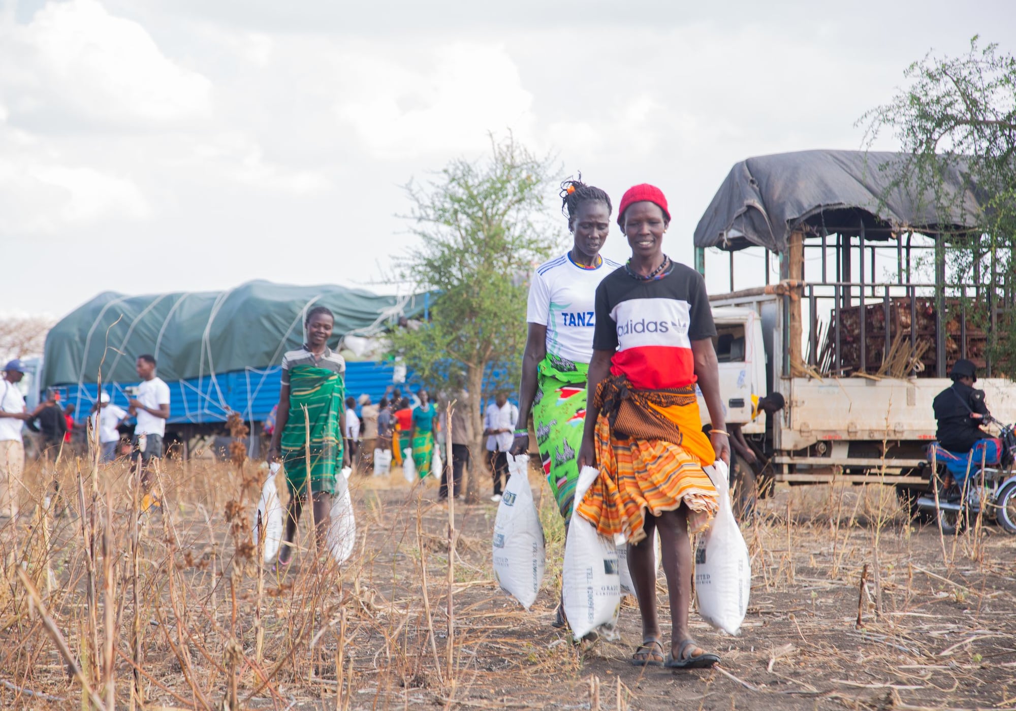 Women carrying sacks of food away from a distribution point