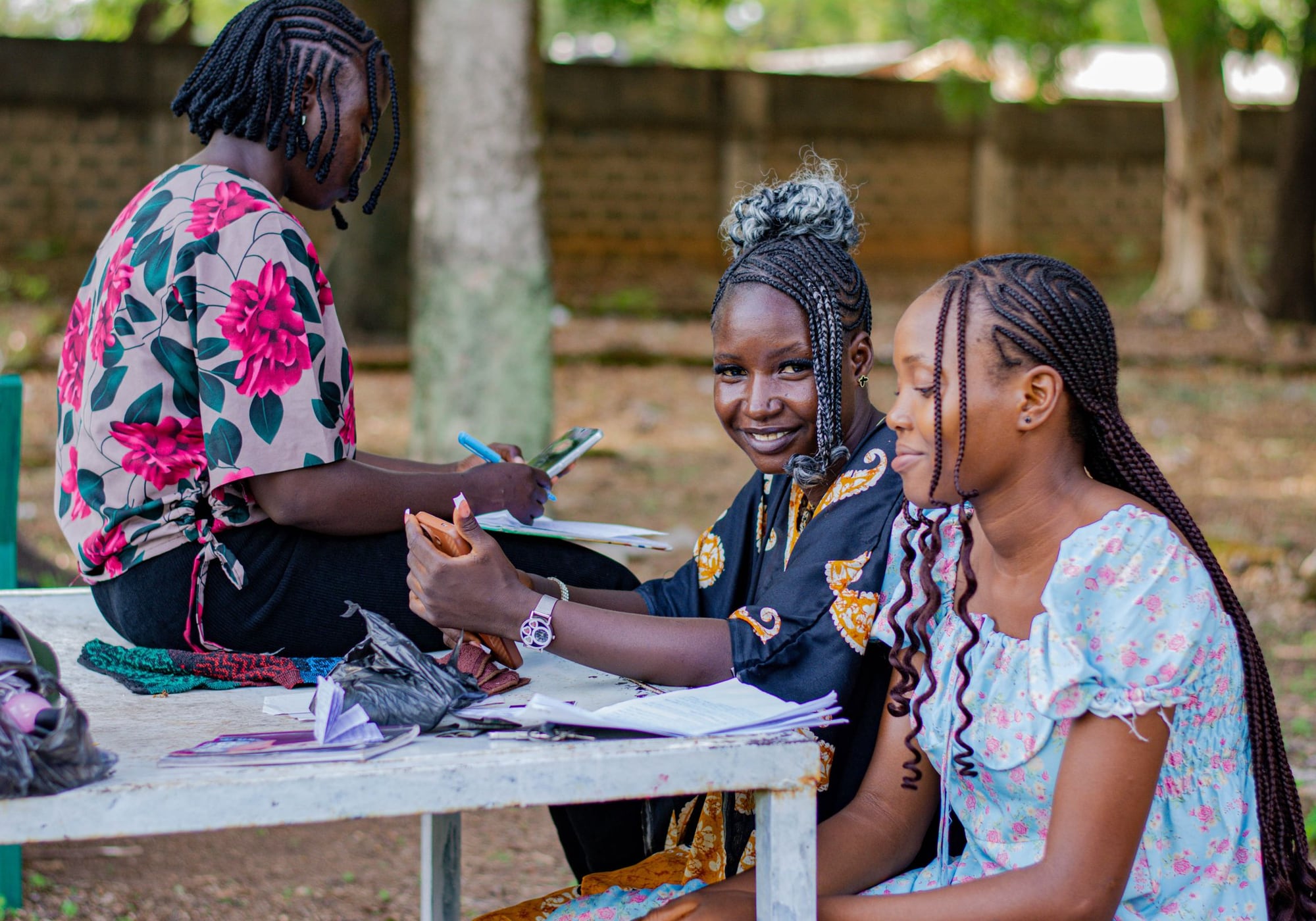 Women working through notebooks and papers at an outdoor table